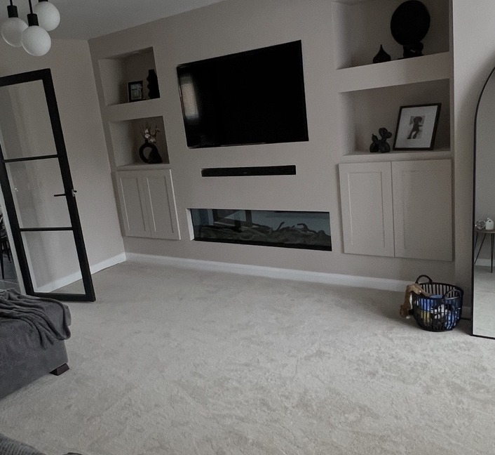 Media wall with integrated shelving and warm lighting.